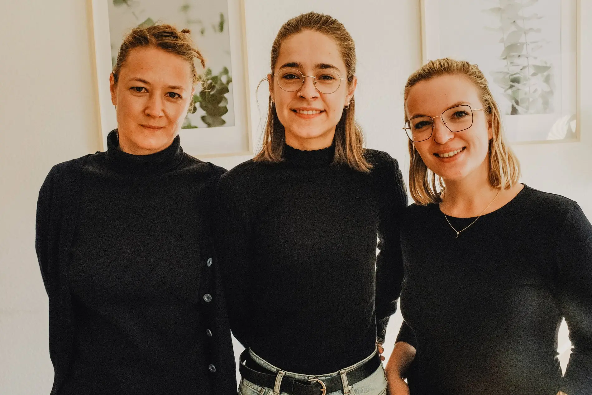 Drei junge blonde Frauen in schwarzer Kleidung.