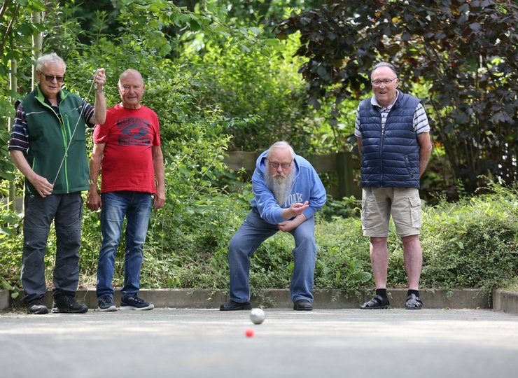 Vier Männer spielen Boule.