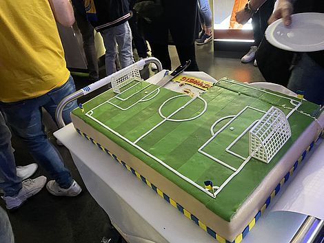 Ein Kuchen in Form eines Fußballfeldes steht auf einem Tisch.