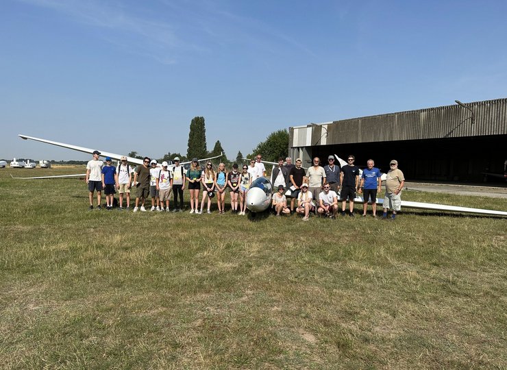 Junge Menschen stehen um ein Segelflugzeug herum. 