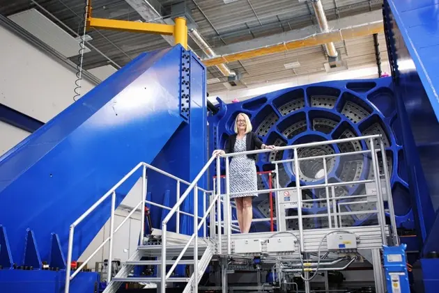 Eine Wissenschaftlerin steht vor einer gewaltigen Machine.