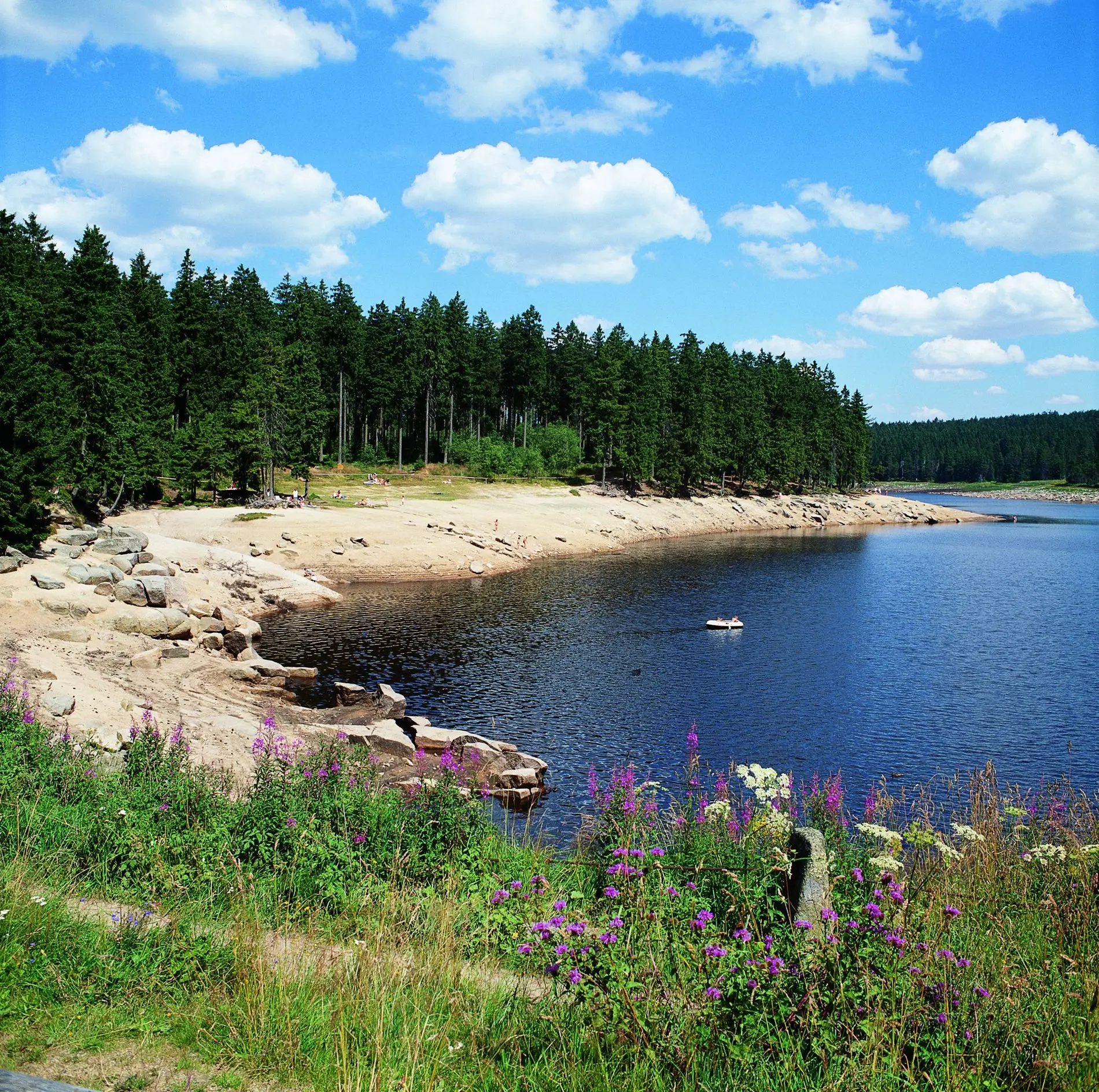 Das Ufer eines Stausees, auf dem Wasser ein Schlauchboot.