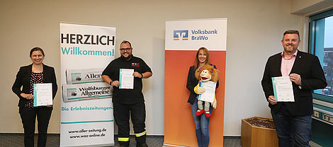 Zwei Männer und zwei Frauen präsentieren in Wolfsburg die Urkunden der „Gemeinsam helfen&quot; - Aktion. 