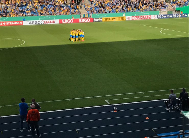 Die Spieler von Eintracht Braunschweig bilden in der Mitte des Spielfelds einen Kreis. 