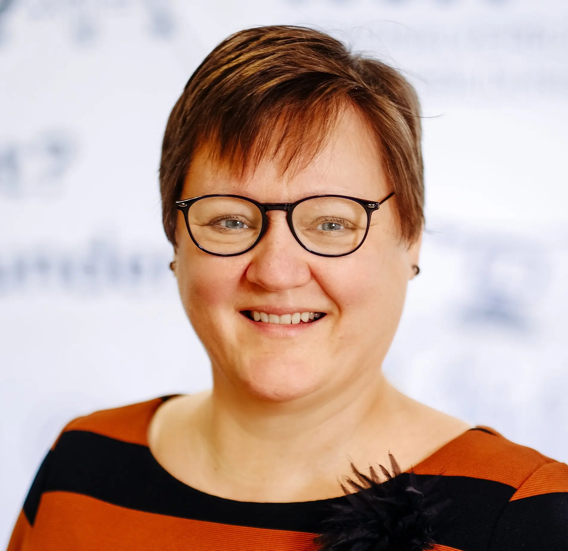 Eine Frau mit kurzen Haaren und Brille.