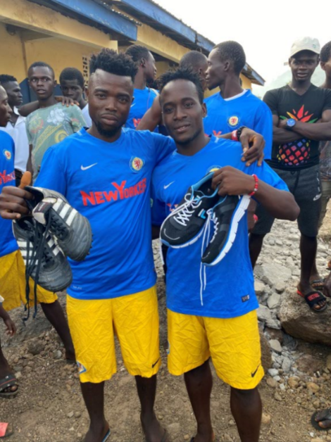 Zwei afrikanische Fußballer halten Fußballschuhe in den Händen.