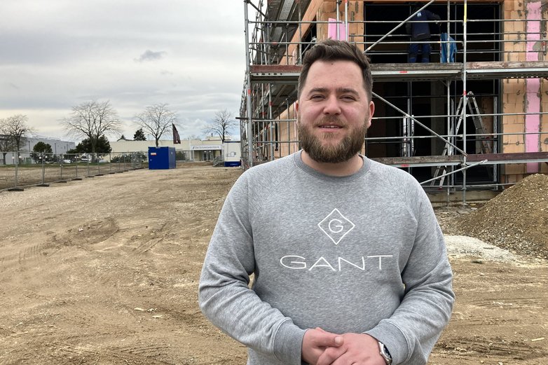 Ein junger Mann steht auf einer Baustelle.