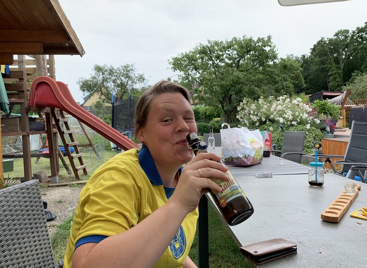Eine Frau in Eintracht Braunschweig-Trikot trinkt Bier aus der Flasche.