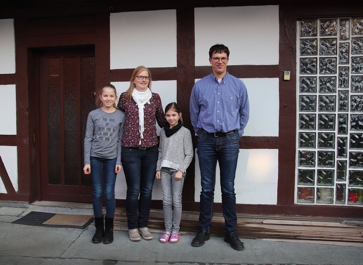 Ehepaar Henkel steht mit seinen beiden Töchtern vor der Außenwand ihres Fachwerkhauses. 