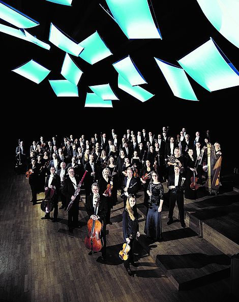 Ein Orchester auf einer Bühne und hellblauen Beleuchtungselementen.