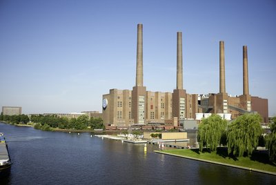 Man sieht die Schornsteine des Volkswagenwerks in Wolfsburg und den Mittellandkanal im Sommer.