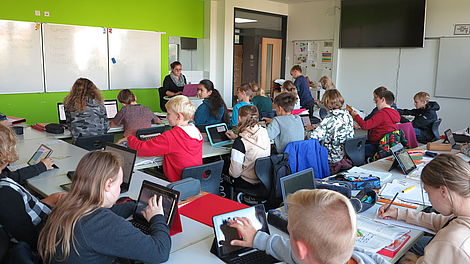 Ein Klassenzimmer mit Schülern, die vor ihre Laptops sitzen.