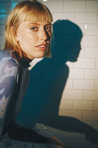 Eine Frau posiert vor einer Wand.