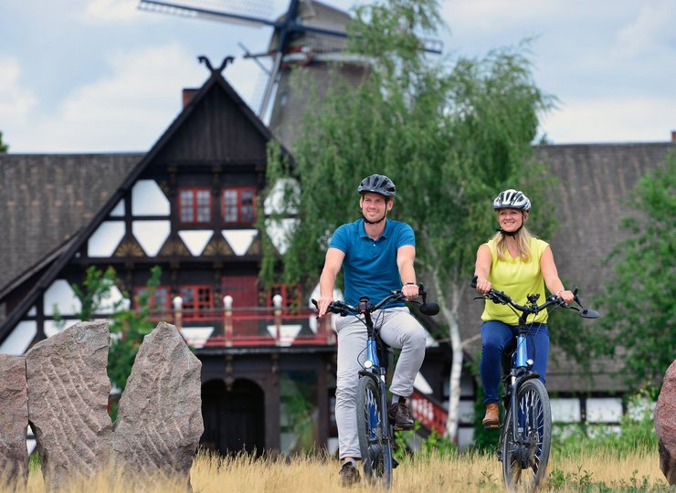 Ein Paar macht eine Rad Tour, im Hintergrund das Mühlenmuseum.