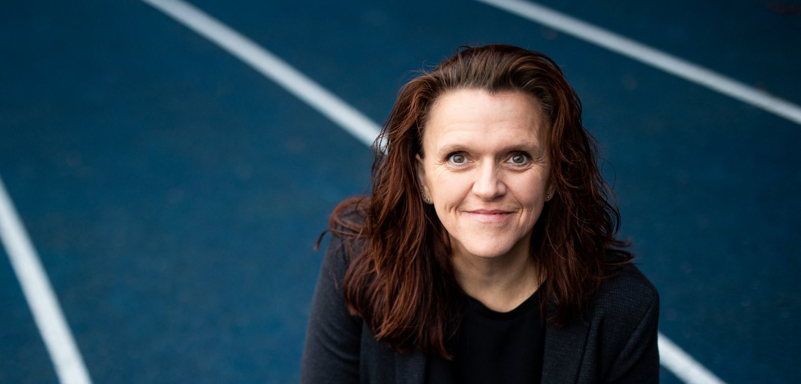 Eine Frau hockt auf einer Aschebahn.