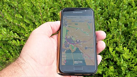 Ein Smartphone in einer Hand, darauf die Kartendarstellung des Naturparks Elm-Lappwald.