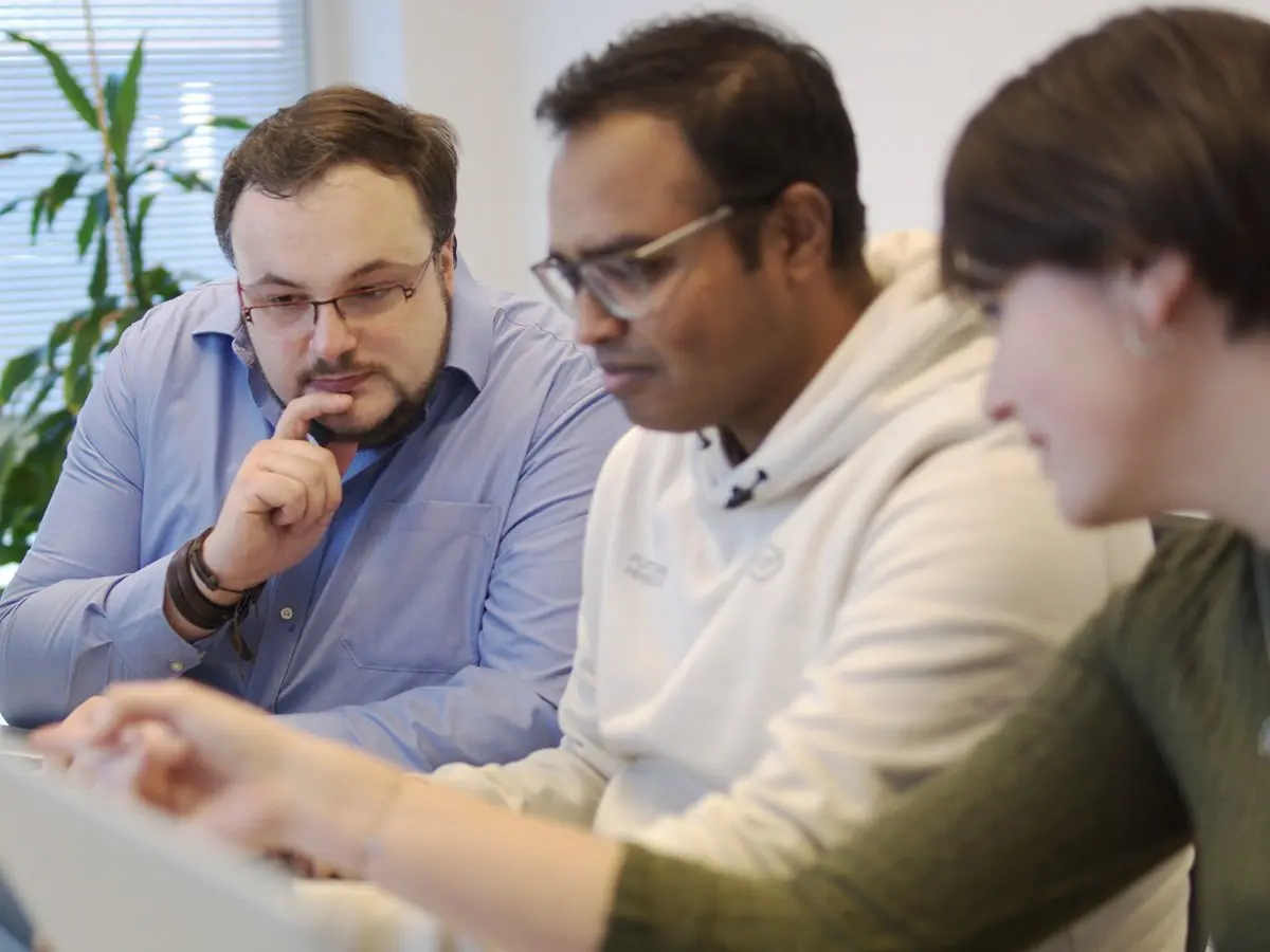 Drei Mitarbeiter der Link Innovations GmbH diskutieren über ein Projekt, welches am Bildschirm angezeigt wird.