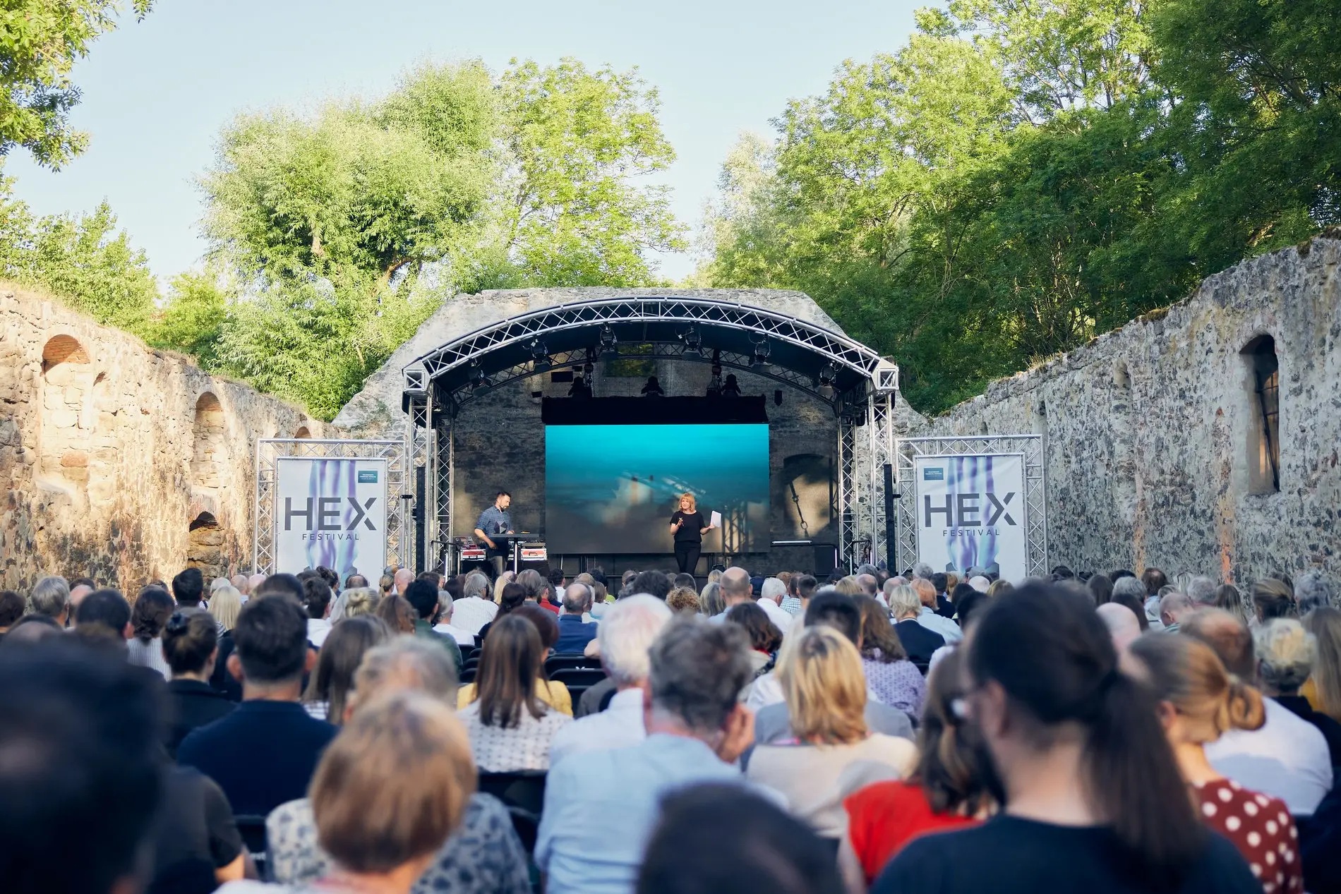Eine Frau und ein Mann stehen auf einer Bühne vor Zuschauern.
