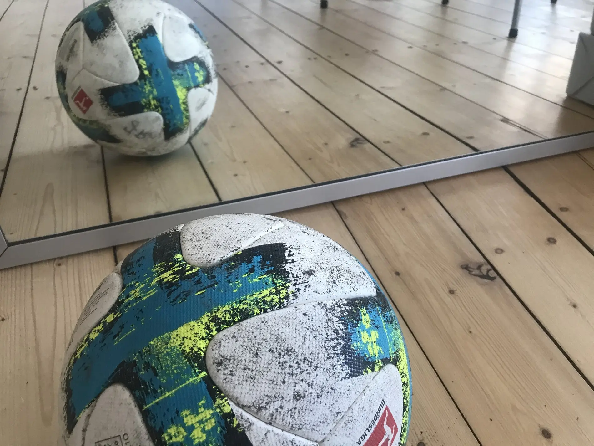Ein Fußball liegt auf dem Boden und spiegelt sich in einem Spiegel.