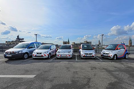 Fünf E-Autos stehen nebeneinander auf einem Parkplatz.