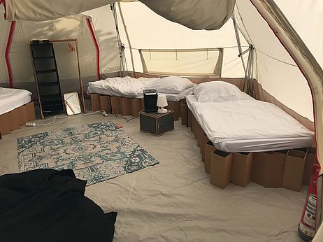 Mehrere Betten stehen in einem geräumigen Zelt.