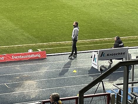 Ein Fußballtrainer steht am Rande eines Fußballfeldes.