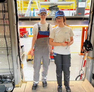 Zwei junge Auszubildende stehen im Türrahmen eines noch nicht fertigen Zuges in der Werkhalle von Alstom. (Bildrechte: Torben Dietrich)