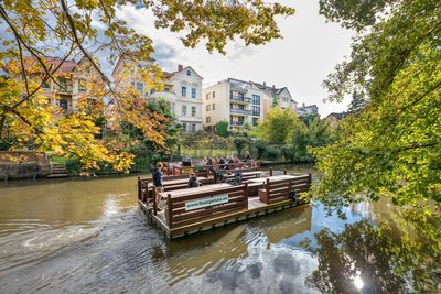 Man blickt auf die Oker, auf der zwei Flöße in diesem Augenblick aneinander vorbeifahren.
