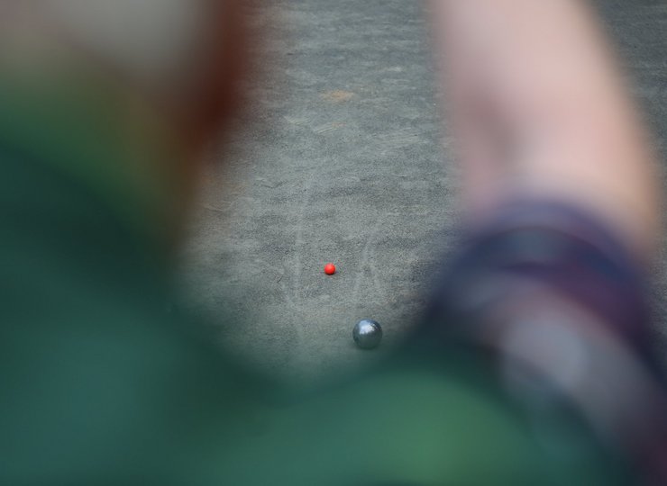 Ein Mann versucht mit einer Boule Kugel so nah wie möglich ans Ziel zu kommen.