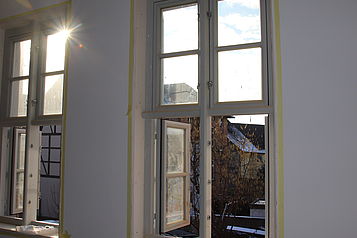 Blick auf die frisch renovierten Fenster eines Fachwerkhauses in Helmstedt mit Blick auf weitere Fachwerkhäuser in der Umgebung.