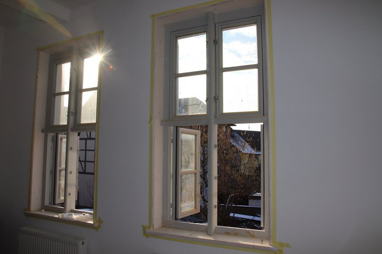 Blick auf die frisch renovierten Fenster eines Fachwerkhauses in Helmstedt mit Blick auf weitere Fachwerkhäuser in der Umgebung.