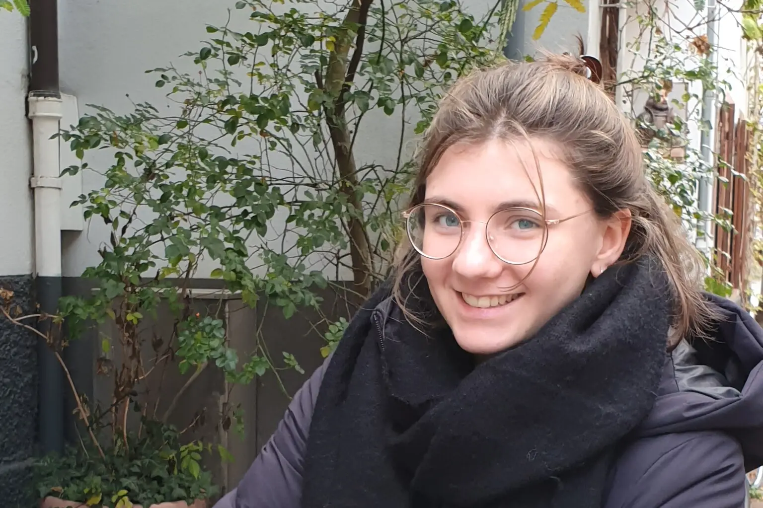 Eine junge Frau mit Brille schaut in die Kamera.