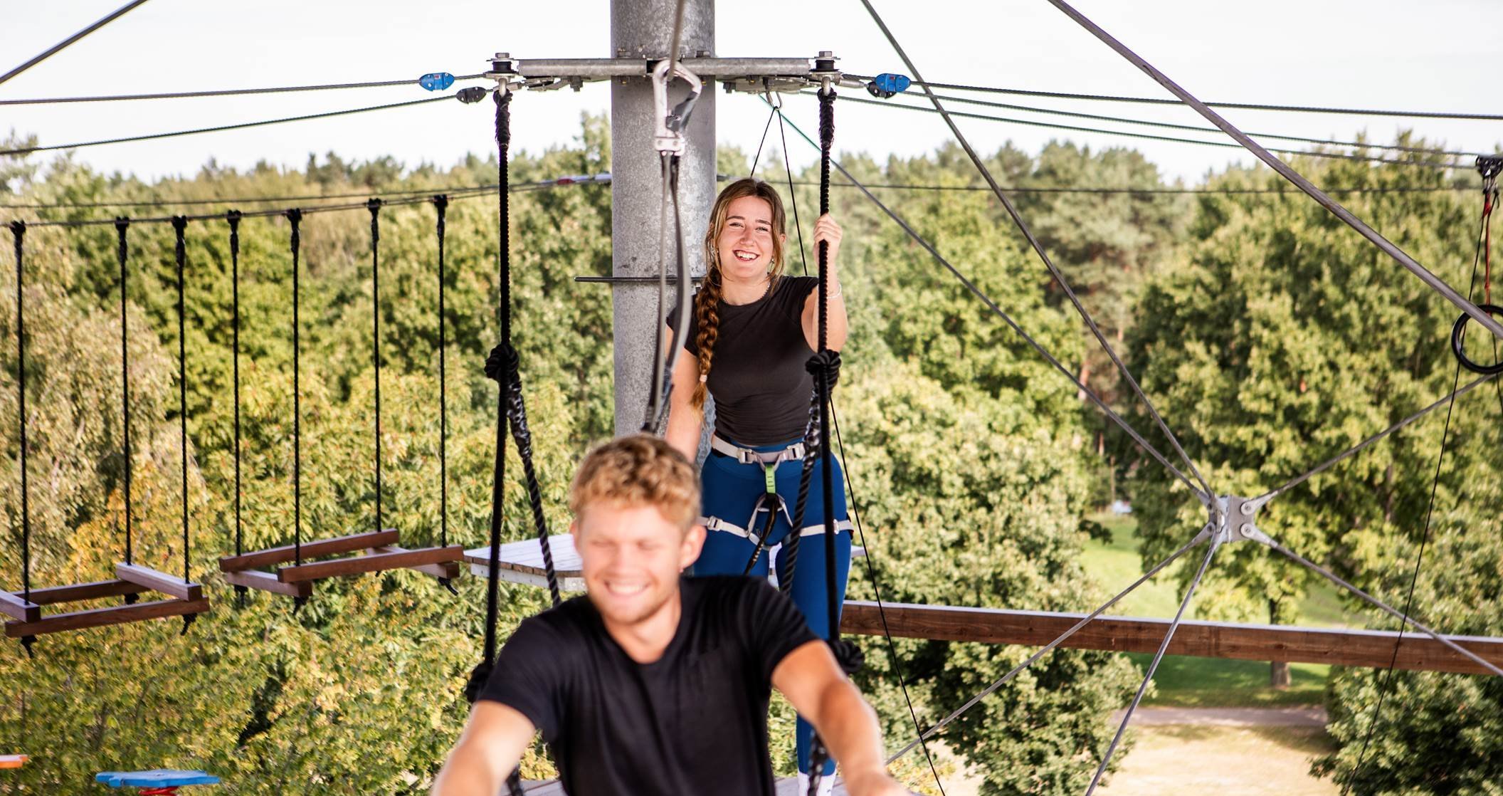 Ein junges Paar klettert auf dem Erlebnisturm am Tankumsee.