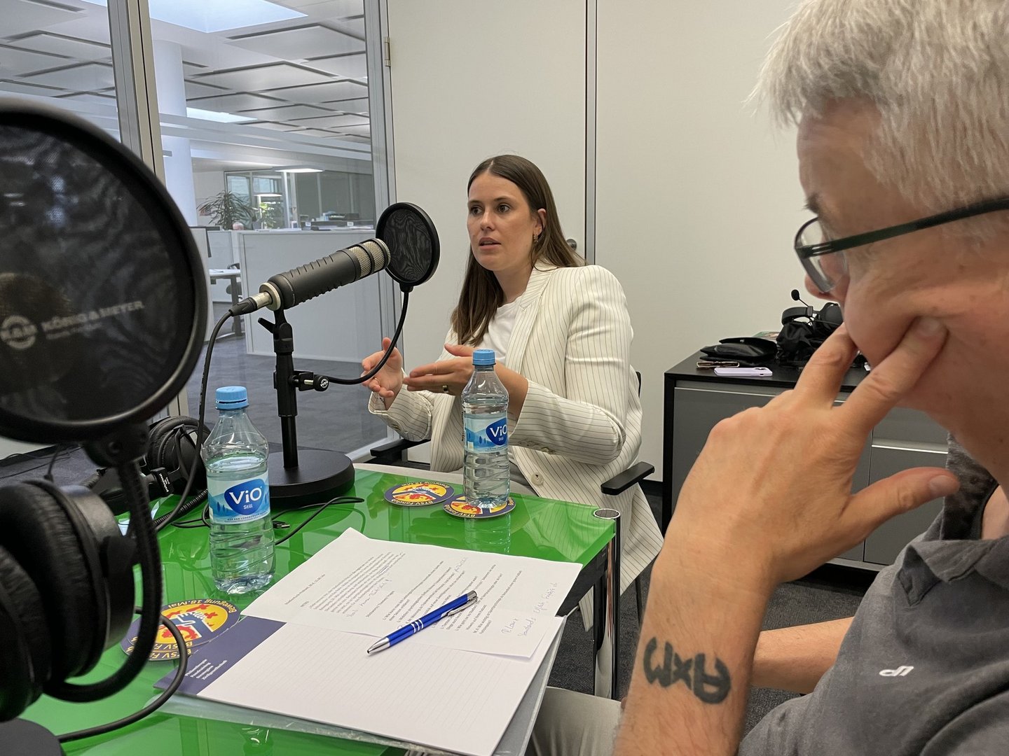 Eine Frau redet vor dem Mikrofon, ein Mann hört zu. 