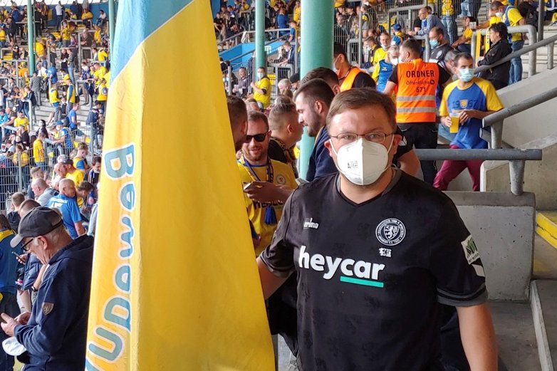Ein Eintracht-Fan steht auf der Tribüne und hält eine Fahne in der Hand.