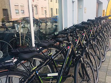 Mehrere gleiche E-Bikes stehen in Schöningen vor einer Ladenzeile.