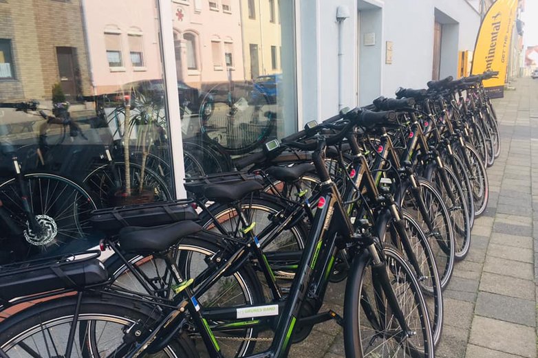 Mehrere gleiche E-Bikes stehen in Schöningen vor einer Ladenzeile.