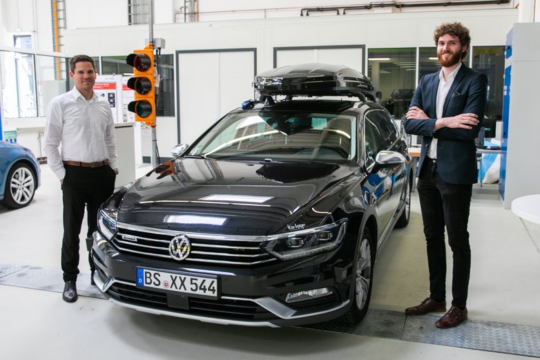 Thomas Ahlswede-Brech (links) und Marcel Kascha links und rechts neben einem schwarzen Testfahrzeug.