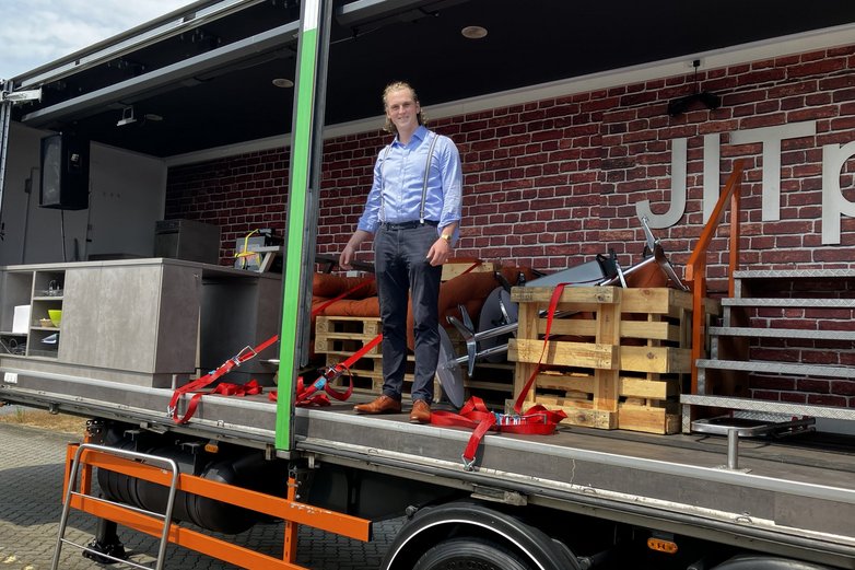 Ein seltenes Bild bei Technologie-Berufe: Ein junger Mann steht auf der Ladefläche eines Truck-Hängers.