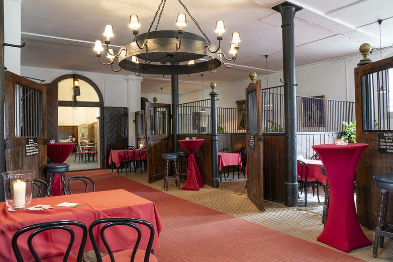 Kulinarik im Pferdestall: Man sieht Tische und einen Verkaufsstand für Speisen