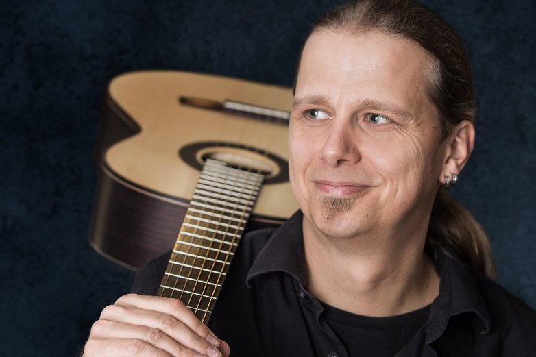 Ein Mann, der eine Gitarre über der Schulter trägt.