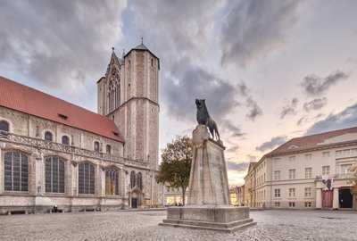 Man blickt auf den Braunschweiger Löwe auf dem Burgplatz, im Hintergrund der Dom St. Blasii