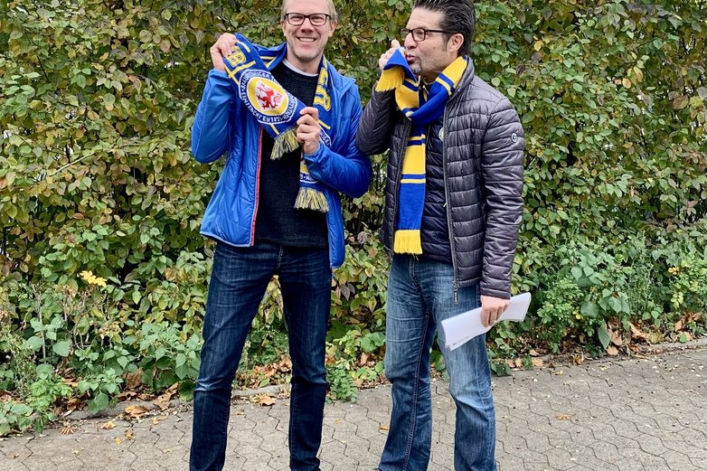 Zwei Eintracht-Fans mit Schal. Einer küsst den Schal.