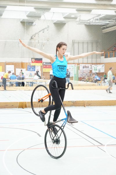 Eine junge Frau vollführt ein Kunststück auf dem Fahrrad.