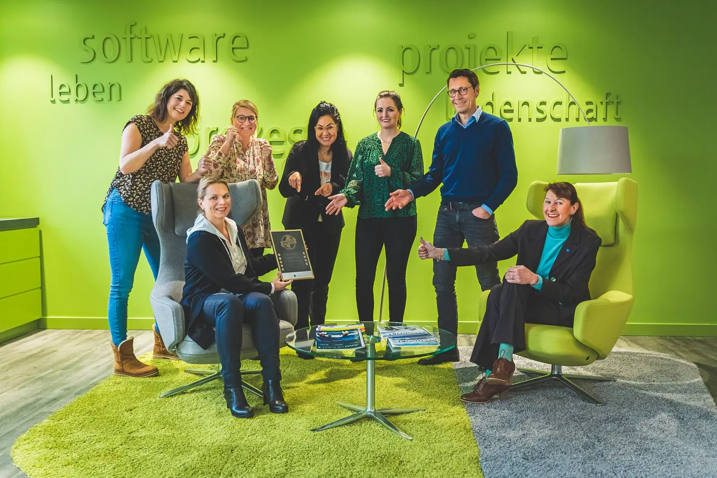 Eine Gruppe von Menschen sitzt und steht, schaut in die Kamera, ein Siegel ist sichtbar.