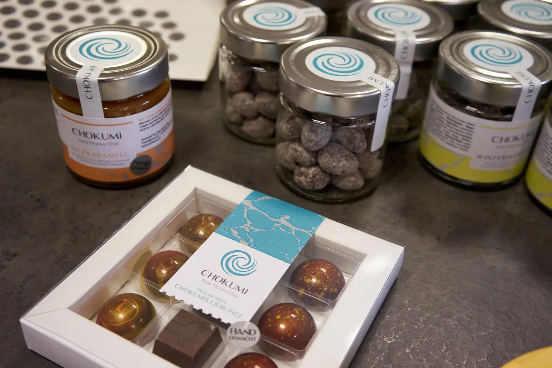 Frisch verpackte Pralinen in Gläsern und einer flachen Packung. 