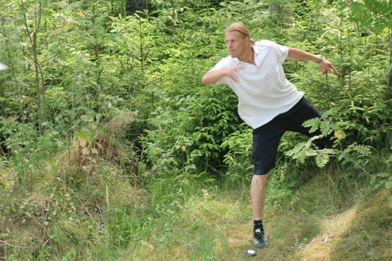 Mann spielt Discgolf in der Natur