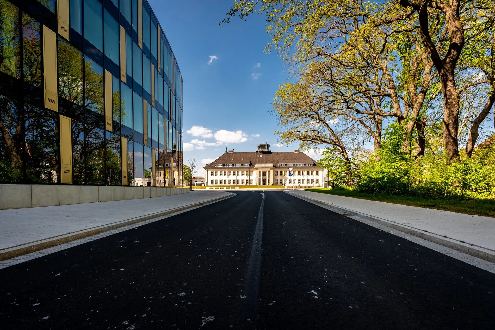 Straße, die auf das historische Flughafengebäude zuläuft. Links das Lilienthalhaus.