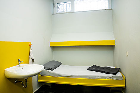 Eine Haftzelle mit gelber Pritsche.