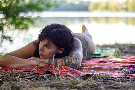 Eine junge Frau liegt am Wasser und entspannt. 